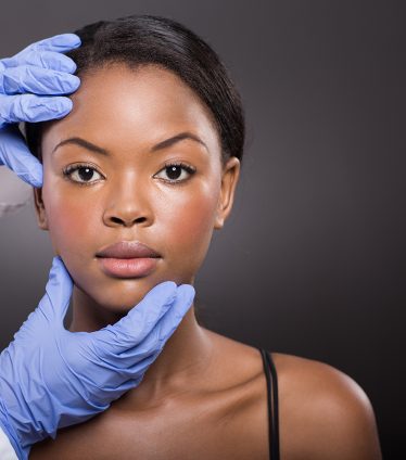 dermatologist checking pretty african woman face skin